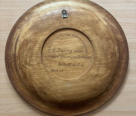 Kārlim Zariņam pasniegtais dekoratīvais koka šķīvis no baltiešu invalīdiem Bedburgas nometnes apmeklējuma laikā. 1949. gada 24. aprīlis. Avots: DVF LKVK.