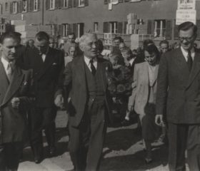 Sūtņa un ārkārtējo pilnvaru nesēja Kārļa Zariņa vizīte Eslingenā, Vācijā. 1949. gada oktobris. Viņu sagaida nometnes vecākie Jānis Aperāns (no kreisās) un Kārlis Kalniņš (no labās). Avots: LNA_LVA, F2263_1_240, 46. lp.